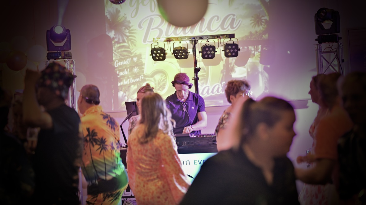 DJ Tonicity draait terwijl gasten dansen op een feest.